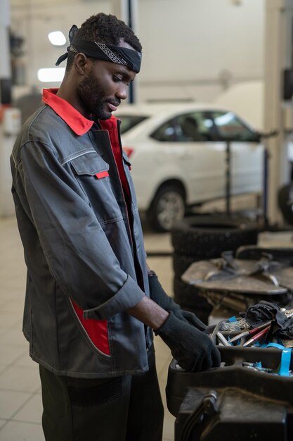 Photo gloved african repairman or technician in workwear taking handtool