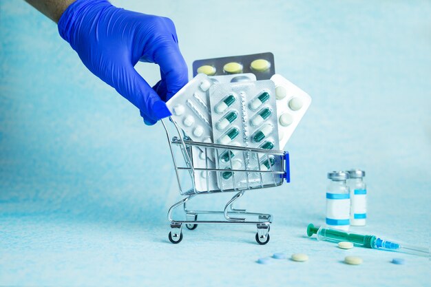 Il corriere guantato consegna un carrello con le pillole ordinate. ordinazione online in farmacia. consegna sicura e senza contatto di medicinali tramite corriere. attività farmaceutica. copia spazio.