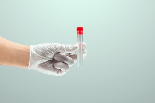 Photo a gloved hand of a doctor holds a test tube with covid-19 vaccine. medical research, close-up.