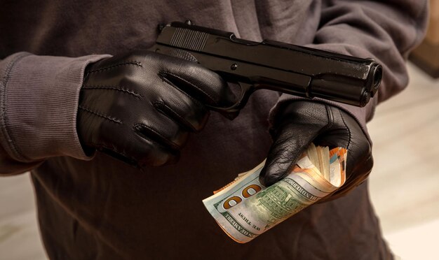 Photo gloved hand holding a pistol stealing money closeup view armed robbery concept