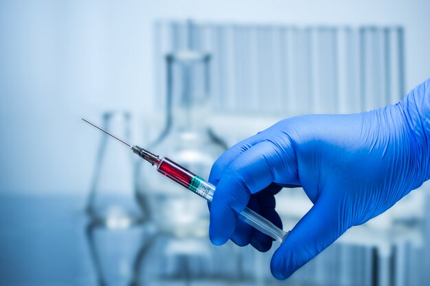 Photo a gloved hand holding a syringe