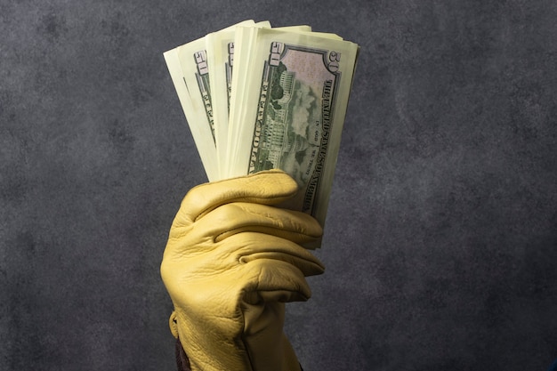 Gloved hand holding a wad of dollars