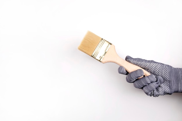 A gloved hand holds a paintbrush. Man paints the walls