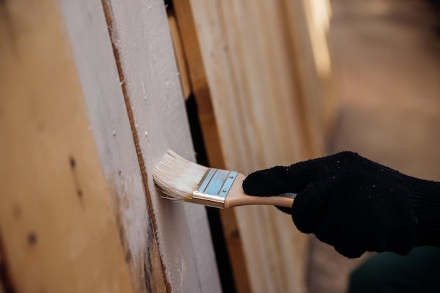 A gloved hand paints a wooden background and boardsPainting works indoors and outdoors