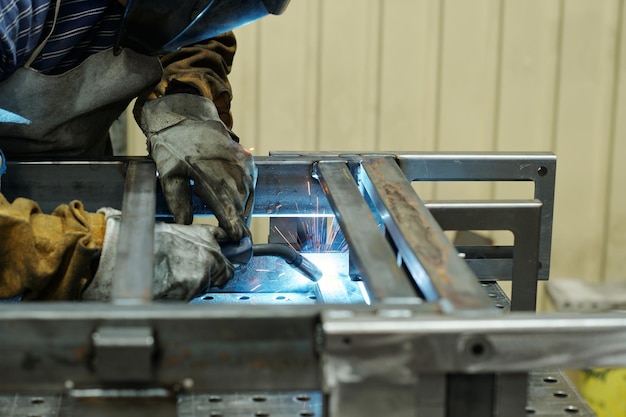 Gloved hands of male worker of industrial plant producing huge machines