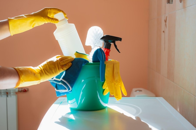 Photo gloved hands take the product from cleaning kit with food and tools in a green bucket