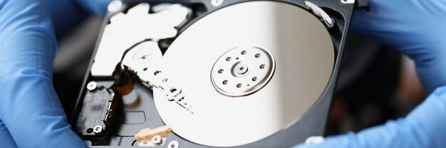 Gloved master holds computer hard drive closeup