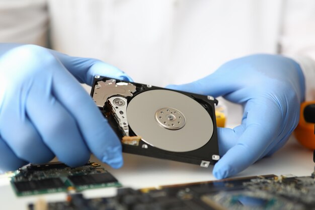 Gloved master holds hard drive away from computer.