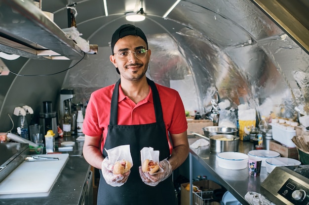 Gloved young man in uniform holding fast food