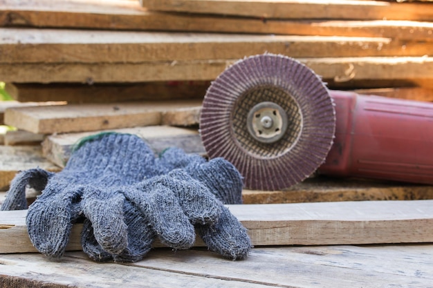 Gloves and electric sandpaper tool on wooden table