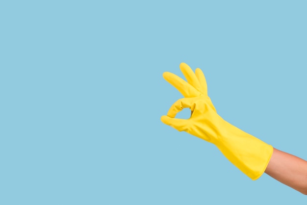 Photo gloves hand with ok gesture sign against blue background