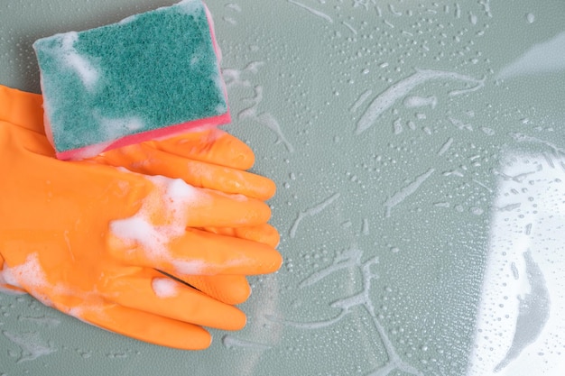 Gloves with a wet sponge for cleaning on glass covered with foam.