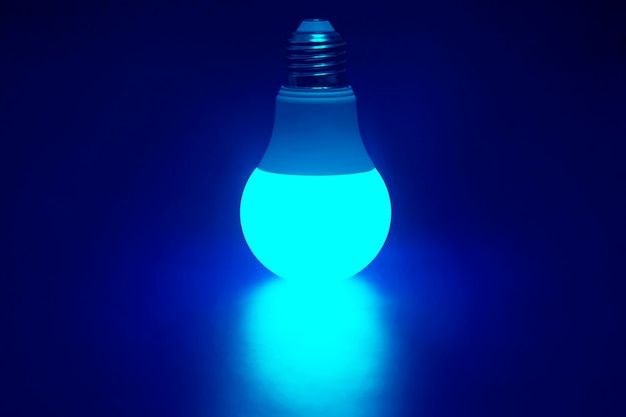 Photo glowing bright green led lamp on a dark blue.