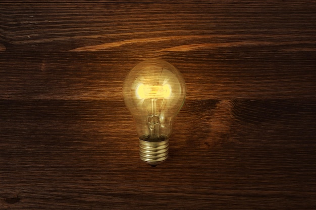 Glowing bulb on the brown wooden background