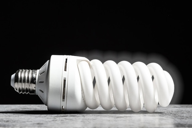 Photo glowing fluorescent bulb light on the grey table on black background