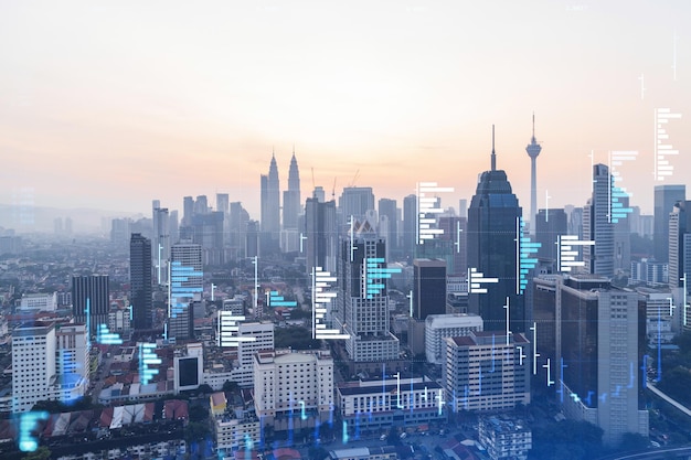 Glowing FOREX graph hologram aerial panoramic cityscape of Kuala Lumpur at sunset Stock and bond trading in KL Malaysia Asia The concept of fund management Double exposure