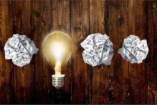 Glowing glass light bulb on wooden background