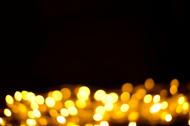 Glowing golden bokeh on a dark background, blur effect. Beautiful festive or Christmas background