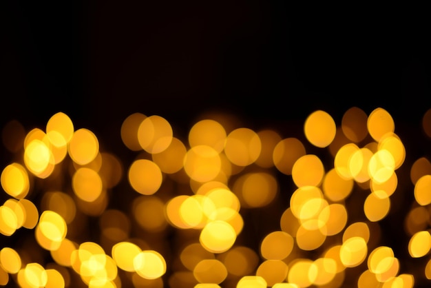 Glowing golden bokeh on a dark background, blur effect. Beautiful festive New Year or Christmas background