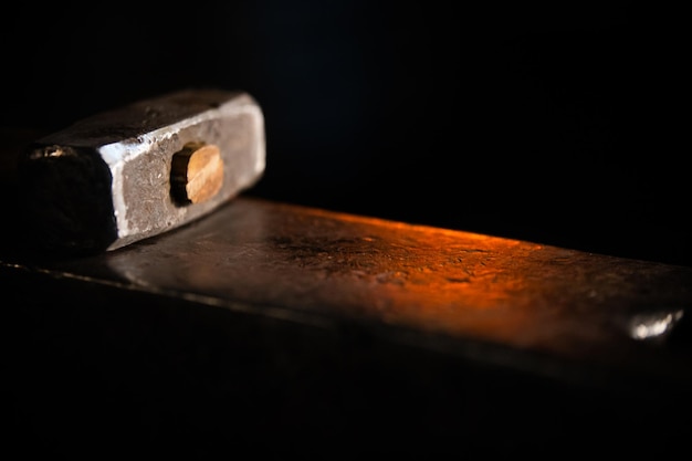 Glowing hammer on the anvil in dark lighting