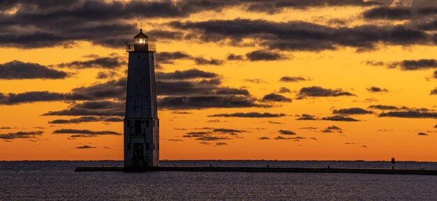 Foto un faro luminoso sotto un tramonto vibrante nella baia