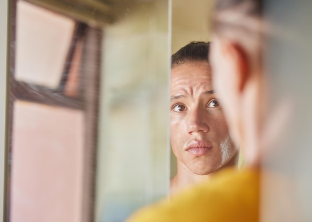 Incandescente e pronto a partire per la giornata inquadratura di un giovane che si guarda il viso nel riflesso del suo specchio nel suo bagno di casa