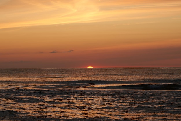 The glowing sun sinking on the horizon of the sea or ocean