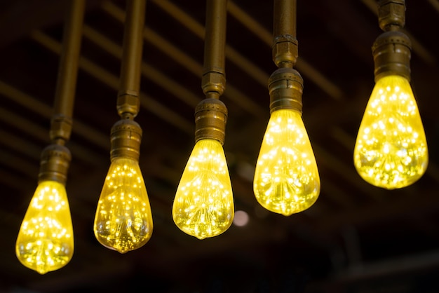 Glowing vintage light bulbs in coffee shop on black background