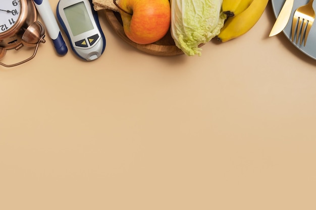 Glucosemeter met bestek en wekker op beige achtergrond met kopieerruimte plat bovenaanzicht