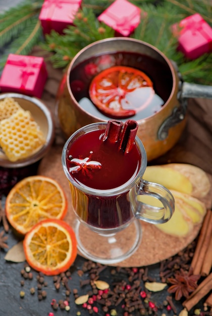 Glühwein, blauwe dennentak en kruiden op houten achtergrond.