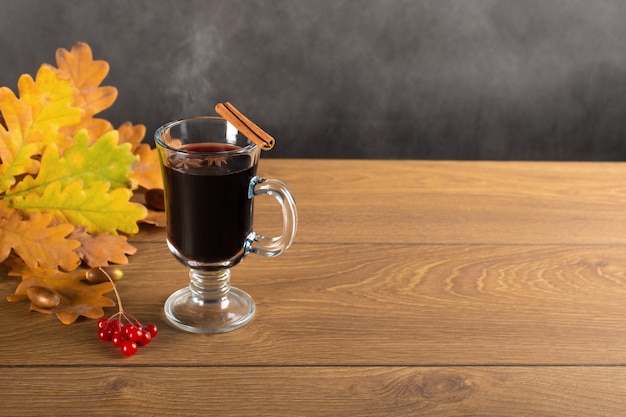 Glühwein en gevallen herfstbladeren. stilleven een mok glühwein met kruiden tegen de achtergrond van gevallen eikenbladeren.