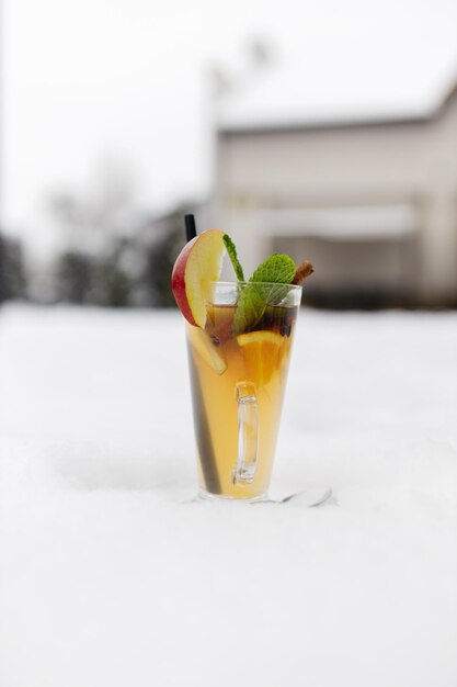 Glühwein in de sneeuw Glühwein in een glazen mok hete rode wijn met sinaasappel- en appelkruiden met kaneel die in een glas giet Mooie witte achtergrond Kopieer ruimte