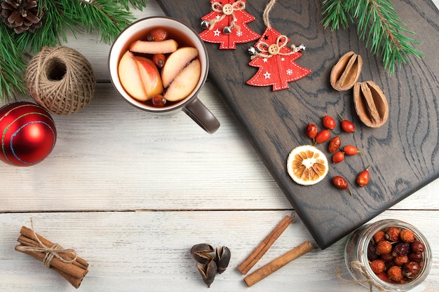 Glühwein in een beker, kaneel, dennentakken en kerstspeelgoed.