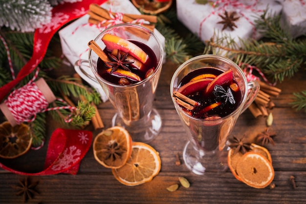 Glühwein met fruit, kaneelstokjes, anijs, decoraties en geschenkdozen op donkere houten achtergrond. Winterverwarmend drankje met receptingrediënten.
