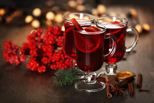 Glühwein met kruiden en kerstboom op houten achtergrond