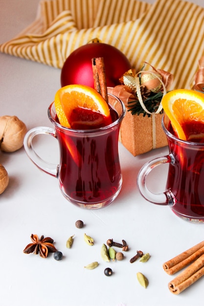 Glühwein met stukjes sinaasappel, kaneelstokjes met kerstballen