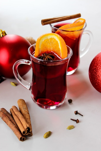 Glühwein met stukjes sinaasappel, kaneelstokjes met kerstballen