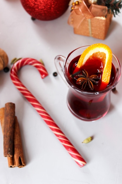 Glühwein met stukjes sinaasappel, kaneelstokjes met kerstballen