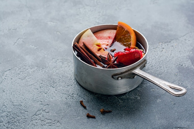 Glühwein warme drank met citrus, appel, granaatappel en kruiden in aluminium braadpan