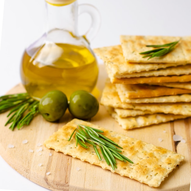 Gluten free crackers with rosemary, olives and olive oil on wooden board