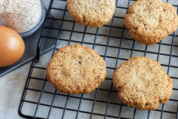 Glutenfree homemade oatmeal cookies, oats, egg on cooling rack. Selective focus. Toned photo.