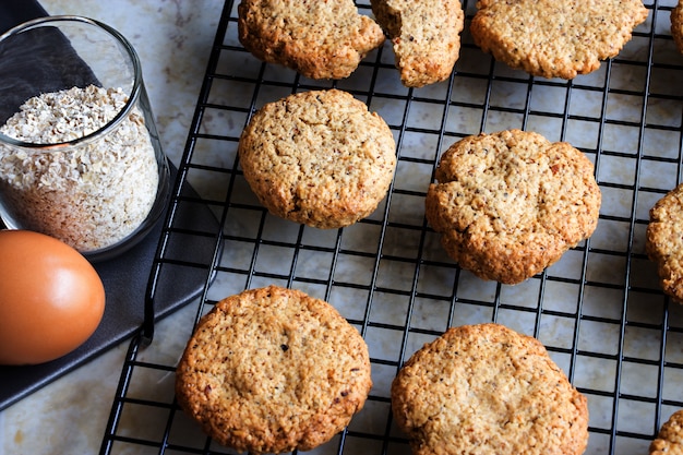 Glutenfree homemade oatmeal cookies, oats, egg on cooling rack. Selective focus. Toned photo