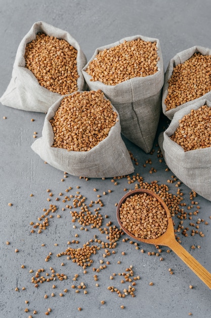 Glutenvrij product. Verticaal schot van droog bruin boekweit voor vegetariërs. Zakken met granen. Houten lepel dichtbij. Heathy eten concept