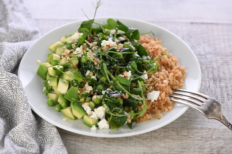 Foto glutenvrije groene vegetarische salade van microgreen sprouts doperwten, avocado, quinoa, spinazie, gekruide amandelschaafsel met plakjes fetakaas