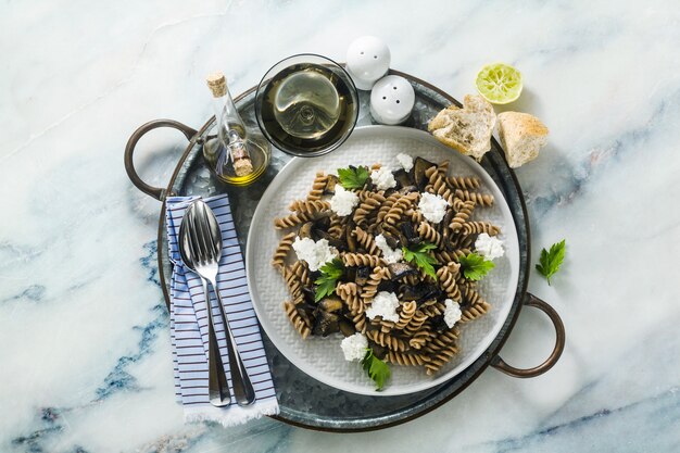 Glutenvrije pasta van half tarwemeel met portobello-champignons en ricotta op een dienblad op een marmeren tafel. gezonde vegetarische recepten