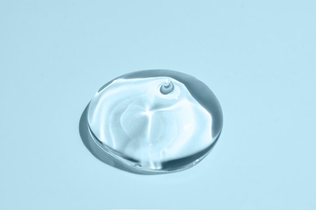 Фото Текстура глицеринного геля прозрачная капля сыворотки на синем фоне жидкий гелевый увлажняющий крем с пузырьками макро