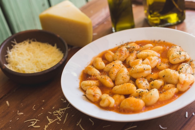 Foto gnocchi alla bolognese, formaggio e olio d'oliva su un tavolo rustico