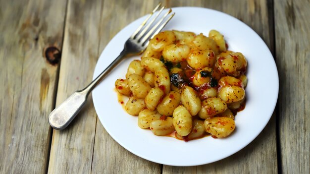 Gnocchi in chili tomato sauce on a white plate.