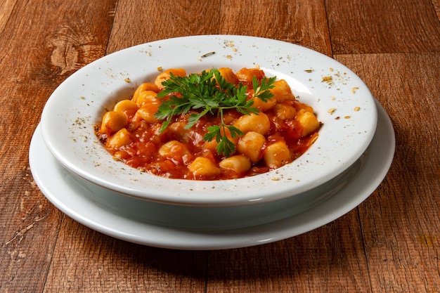 Gnocchi dish with tomato sauce and parsley on rustic wooden table