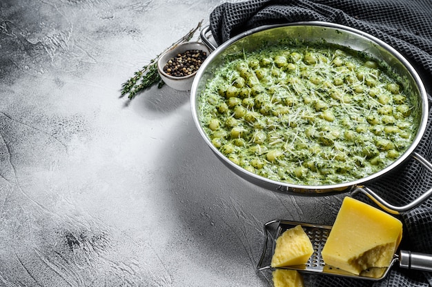 Gnocchi met basilicum spinaziesaus. Italiaanse aardappelpasta. Grijze achtergrond.